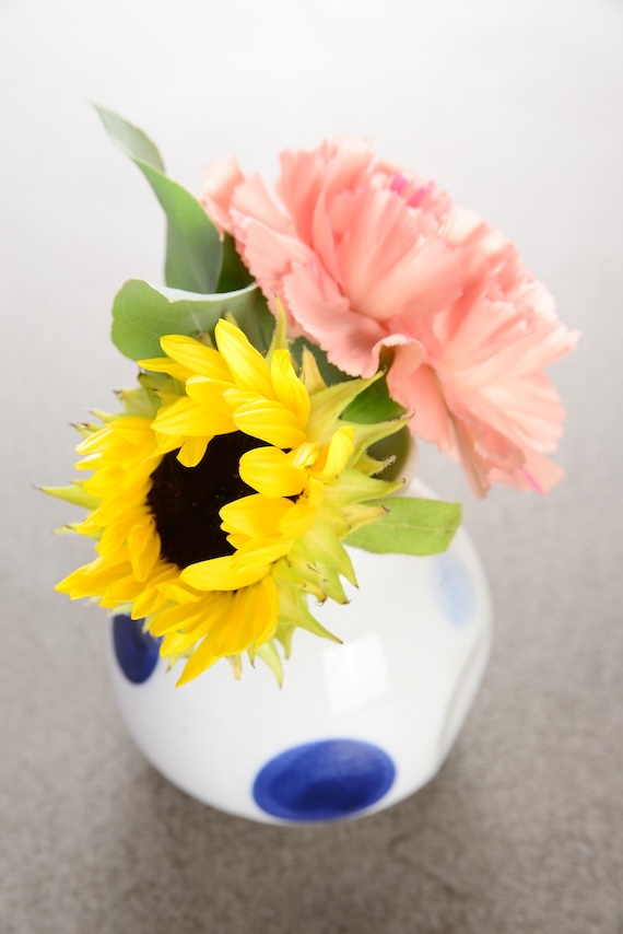 青い水玉の花瓶に咲くひまわりとピンクのカーネーション