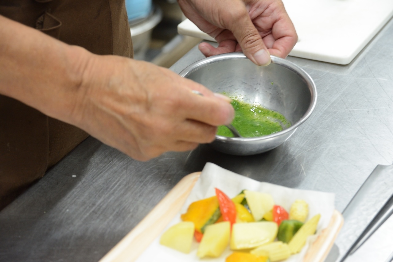 緑のソースを混ぜ合わせる手元と彩り野菜