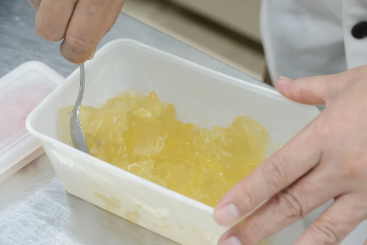 黄金色のジュレをスプーンでほぐす手元