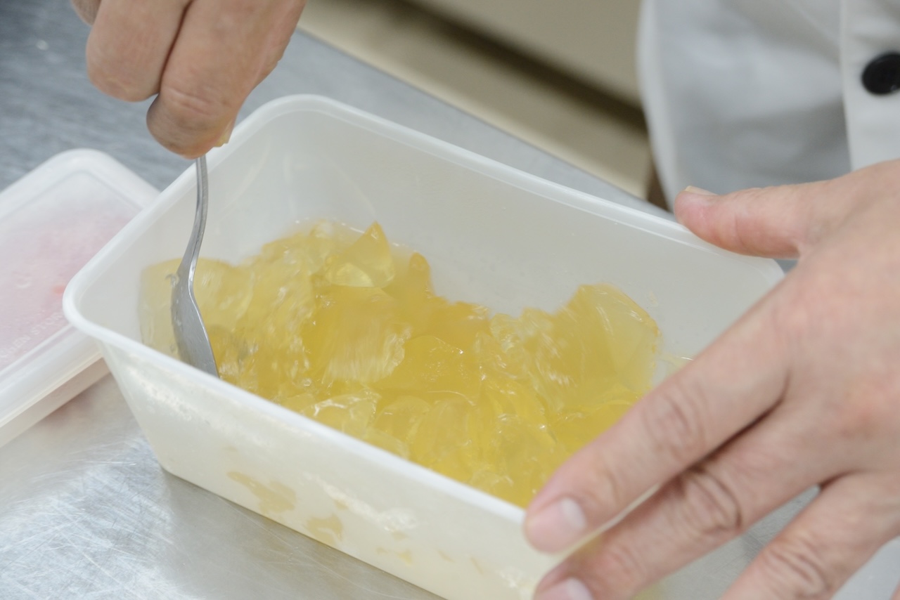 黄金色のジュレをスプーンでほぐす手元