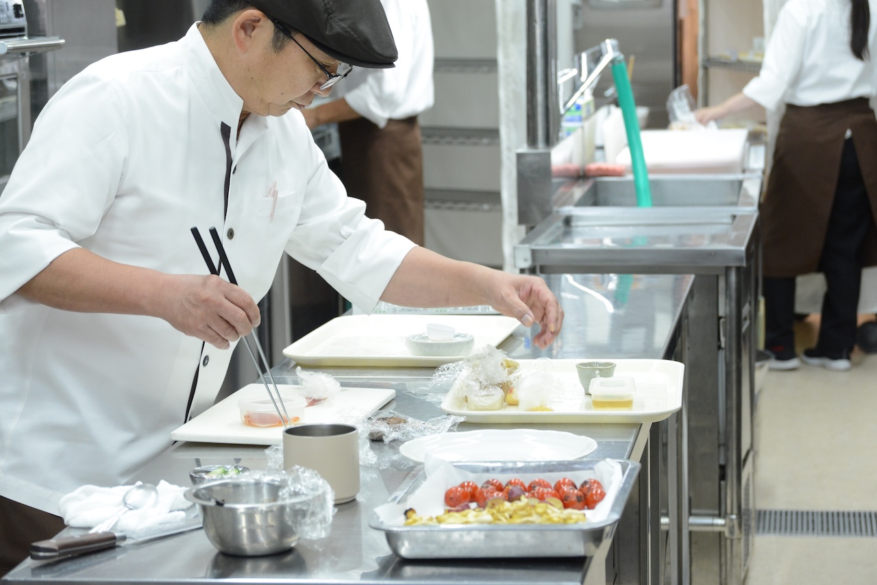 厨房で盛り付けをする料理長