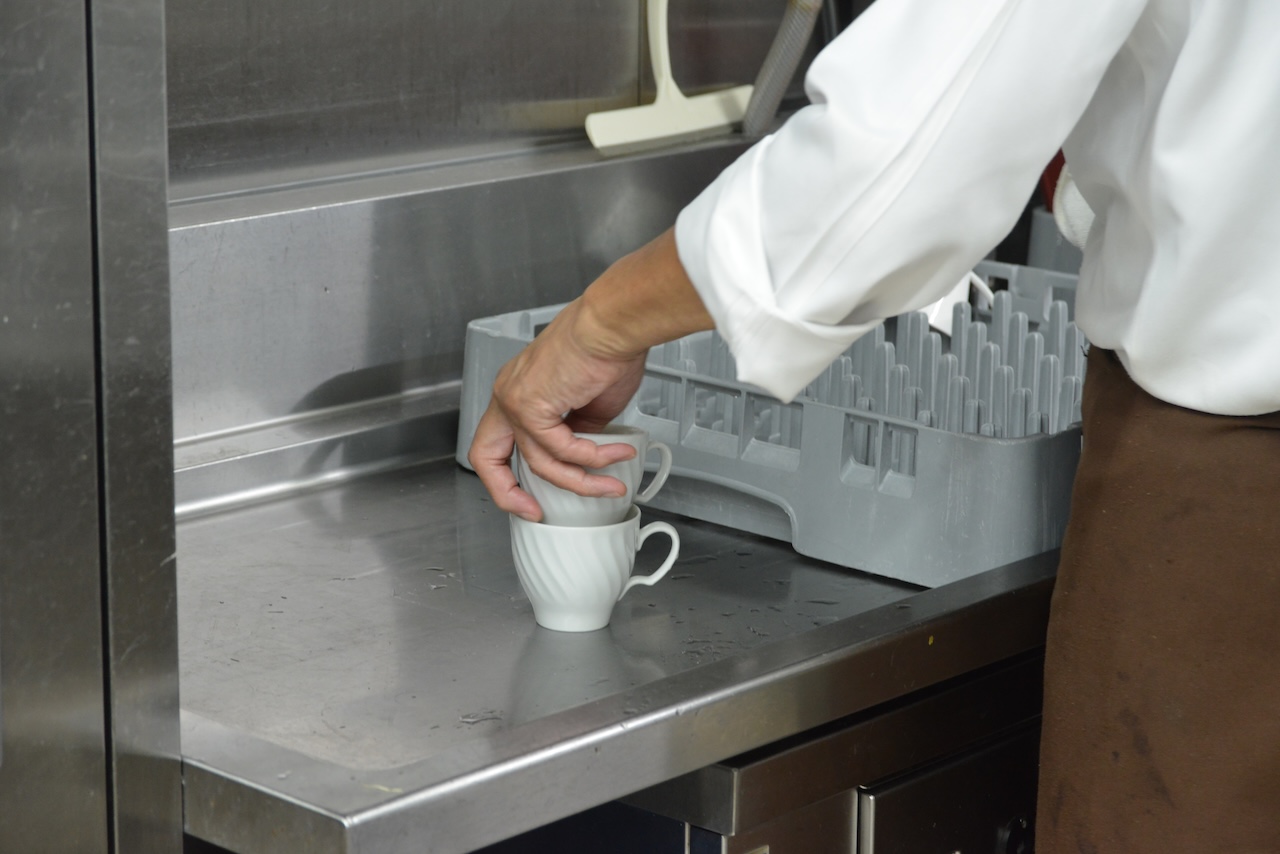 白いカップを整えるスタッフの手元